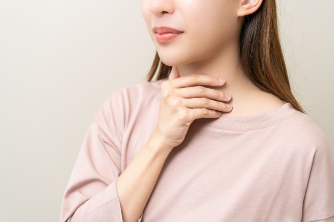 喉に手を当てる女性